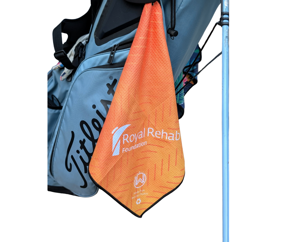 orange corporate charity golf towel with'Royal Rehab Foundation' and wild golf logo hanging from a golf bag